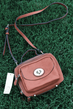 A Brown Purse with an Adjustable Shoulder Strap on the Grass