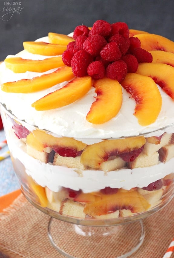 A raspberry peach trifle in a glass serving stand