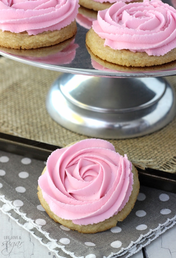 Rosette Sugar Cookies on a silver cake stand with one in front