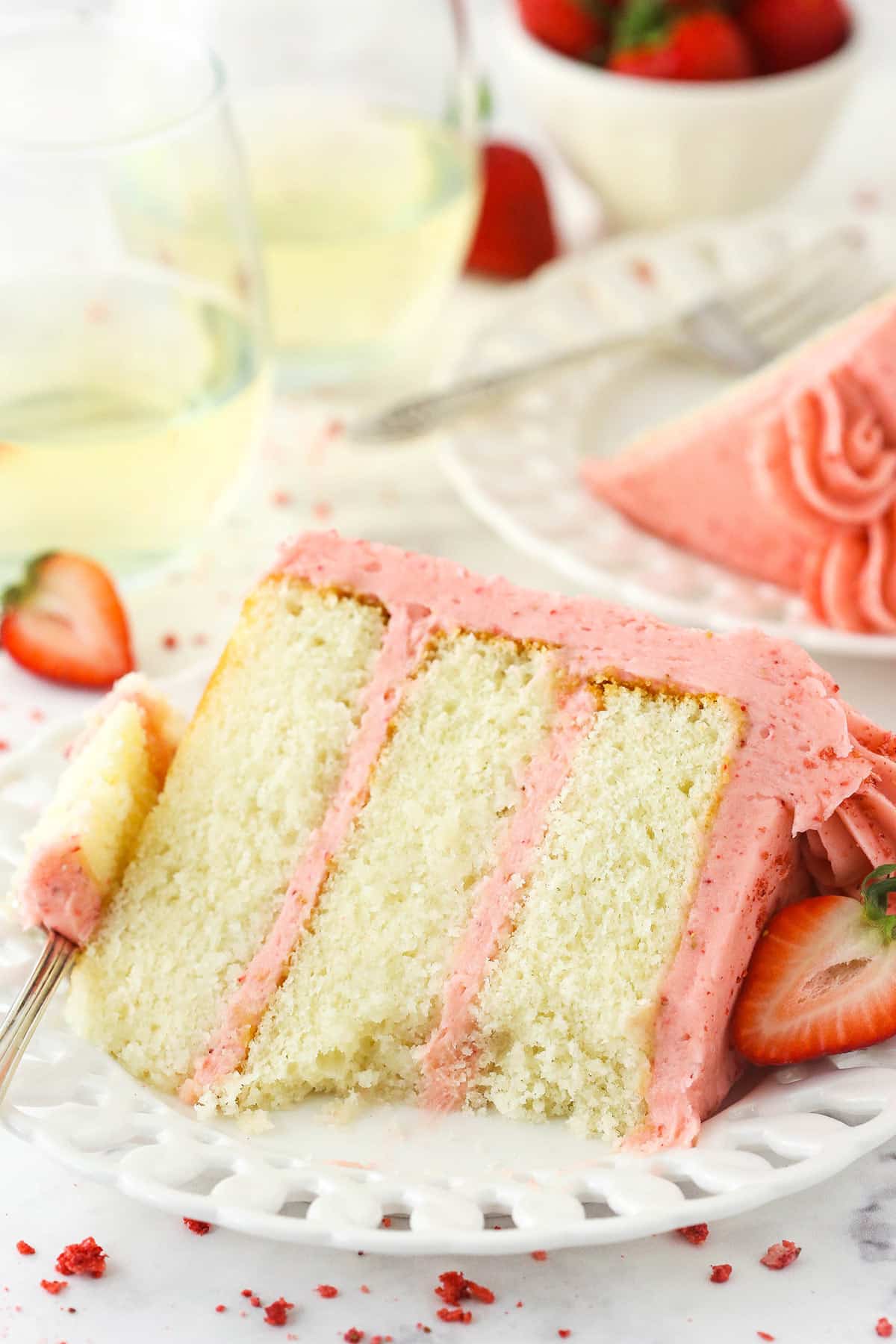 slice of strawberry moscato cake on white plate with a bite taken out