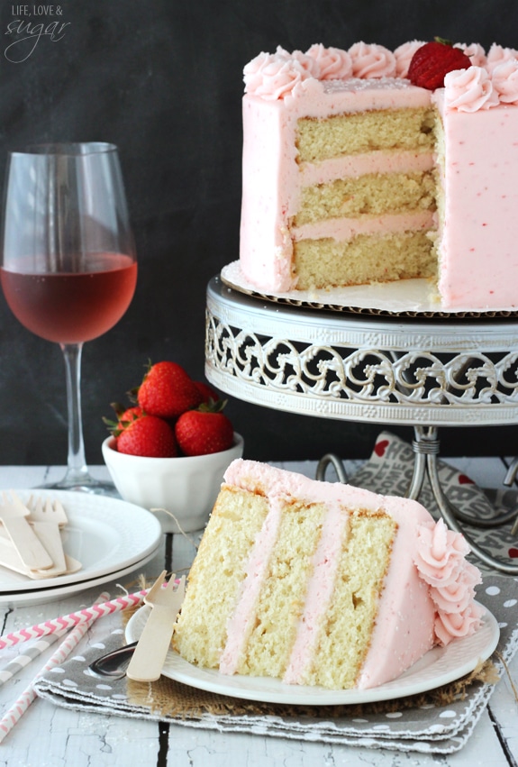 Strawberry Moscato Layer Cake slice on a plate in front of the whole cake