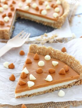 A big slice of White Chocolate Butterscotch Tart on white paper and a fork