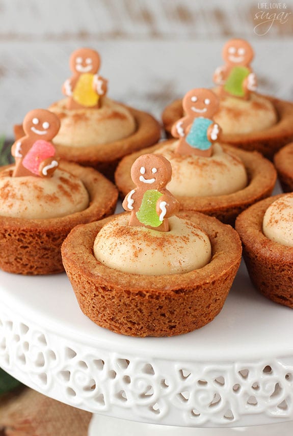 Gingerbread Cheesecake Cookie Cups topped with mini gingerbread cookies on a white cake stand