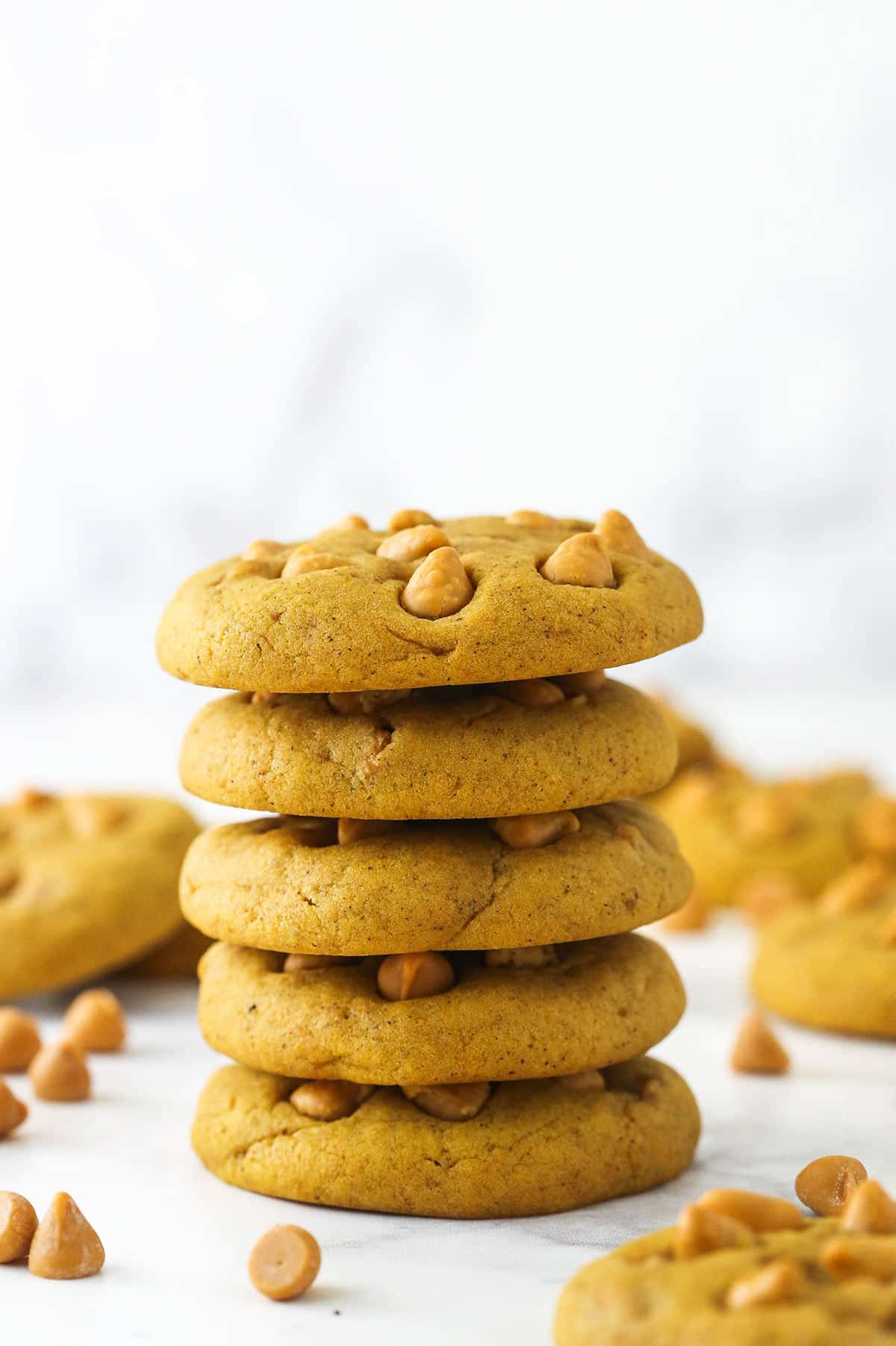 stack of pumpkin cookies with other pumpkin cookies around it