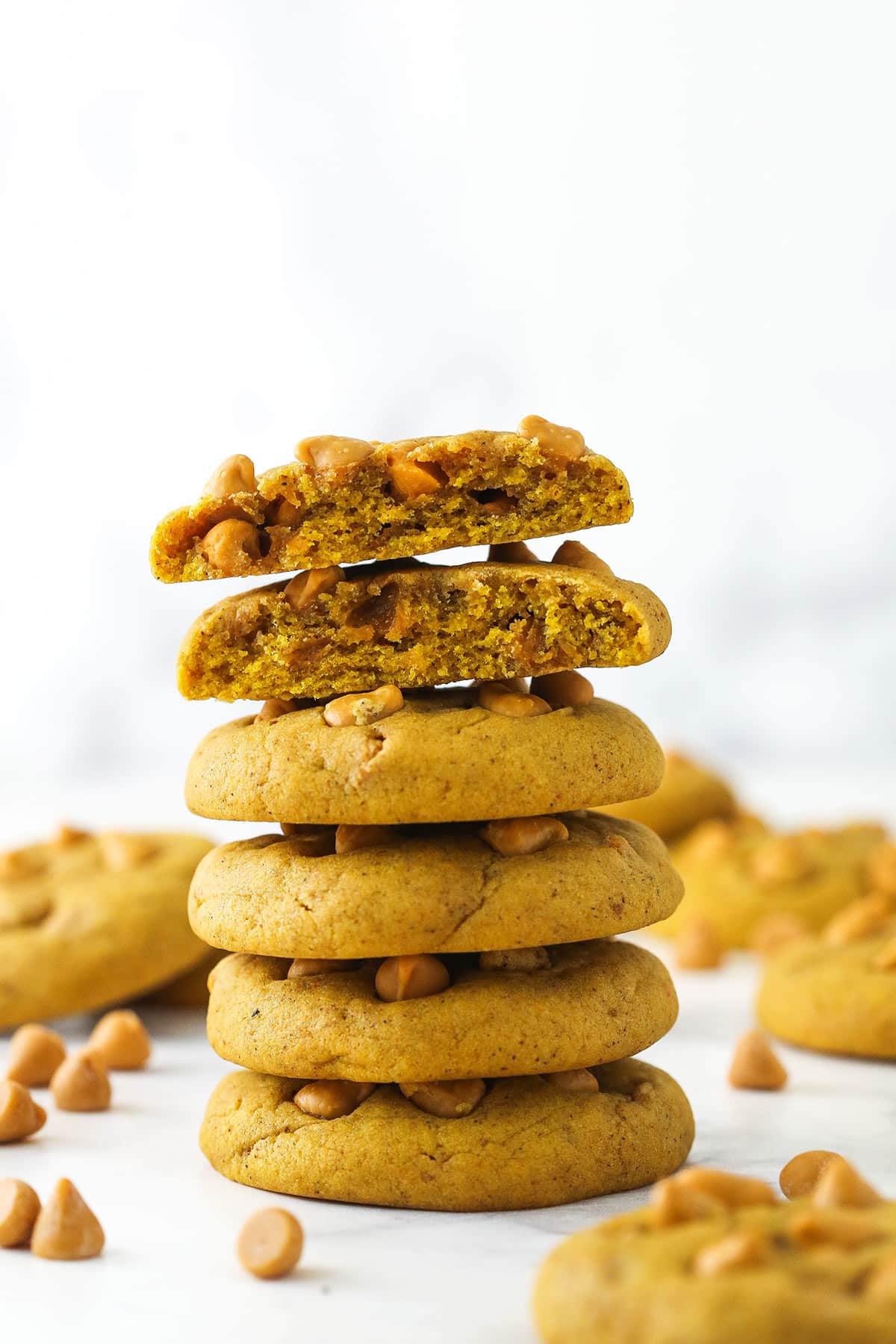 stack of pumpkin butterscotch chip cookies with one broken in half on top