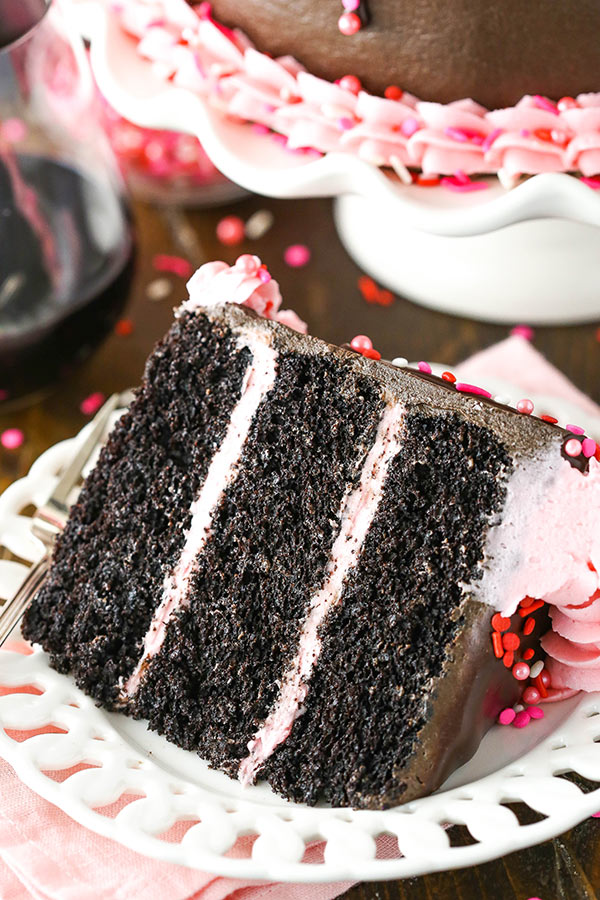 Sliced of chocolate cake with pink buttercream on a plate.