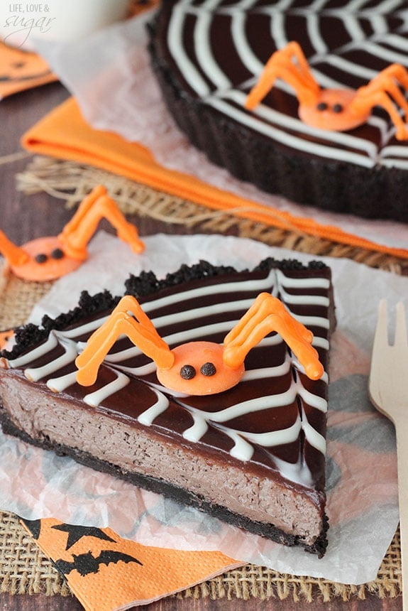 Spiderweb Chocolate Tart slice on a napkin topped with an orange candy spider