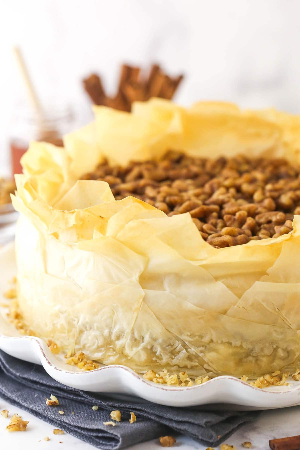 With a phyllo dough crust, creamy cheesecake filling, and honey walnut topping, Baklava Cheesecake is a fun twist on the traditional dessert. Baklava cheesecake on a white platter