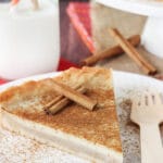 Milk Tart slice on white plate with cinnamon sticks close up