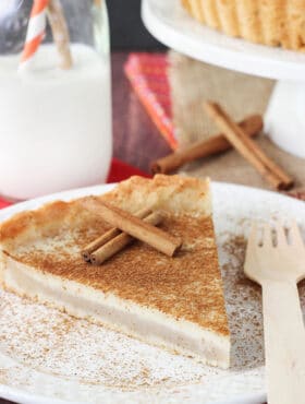 Milk Tart slice on white plate with cinnamon sticks close up