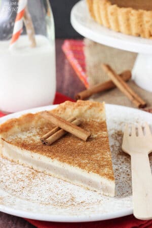 Milk Tart slice on white plate with cinnamon sticks close up