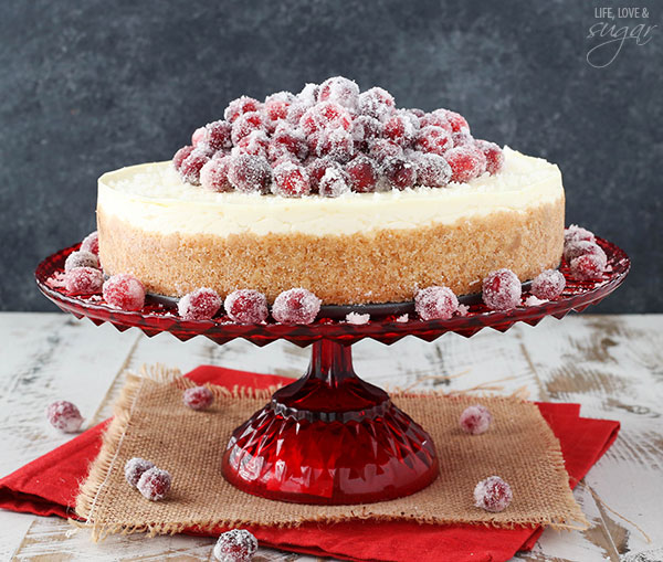 No Bake Sparkling Cranberry Orange Cheesecake on a red cake stand