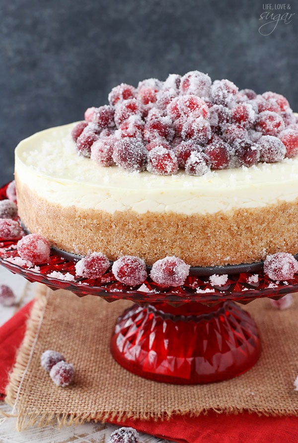 No Bake Sparkling Cranberry Orange Cheesecake on a red cake stand