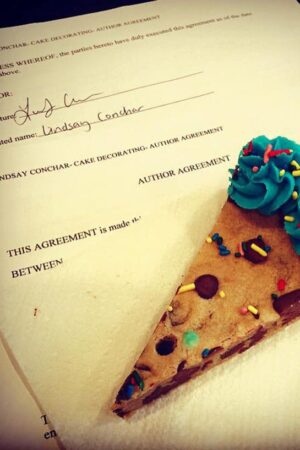 A slice of cookie cake and my authors contract for my new cookbook!