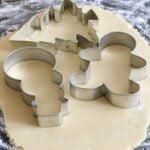 Using festive cookie cutters to cut out sugar cookies.