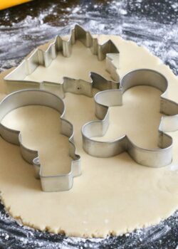 Using festive cookie cutters to cut out sugar cookies.