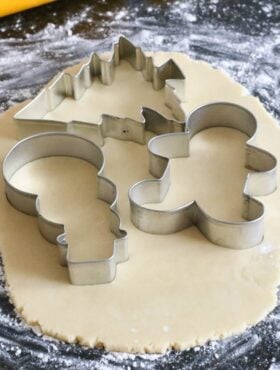 Using festive cookie cutters to cut out sugar cookies.