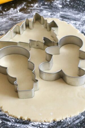 Using festive cookie cutters to cut out sugar cookies.