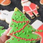 A Christmas tree cut out cookie decorated with royal icing.