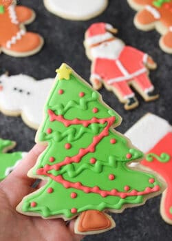 A Christmas tree cut out cookie decorated with royal icing.