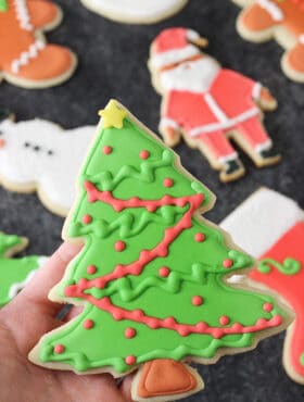 A Christmas tree cut out cookie decorated with royal icing.