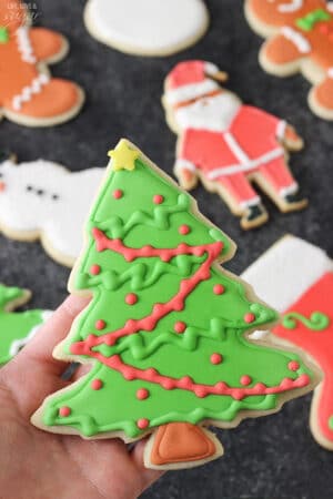 A Christmas tree cut out cookie decorated with royal icing.