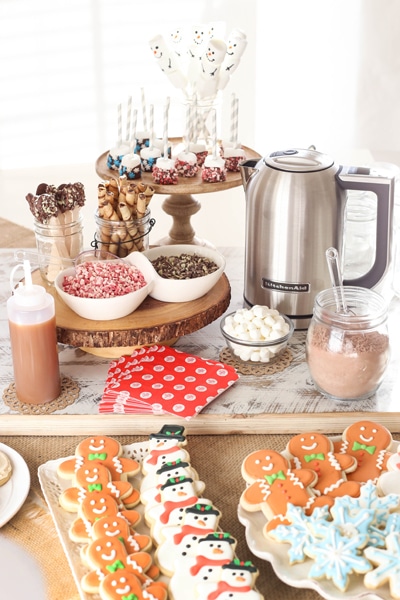hot chocolate bar with cutout cookies, marshmallows, peppermint pieces, chocolate covered spoons