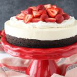 Strawberry Brownie Cheesecake on red stand close up