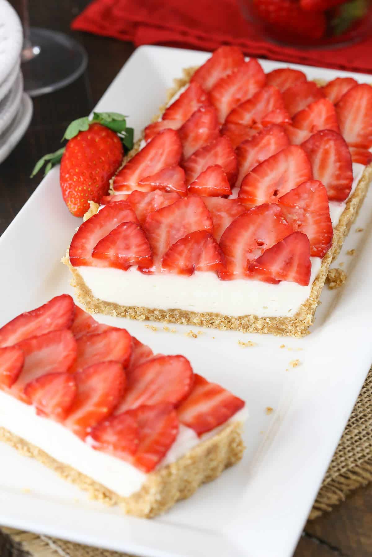 A champagne tart on a long serving platter with one slice missing and a second slice beside the remaining tart