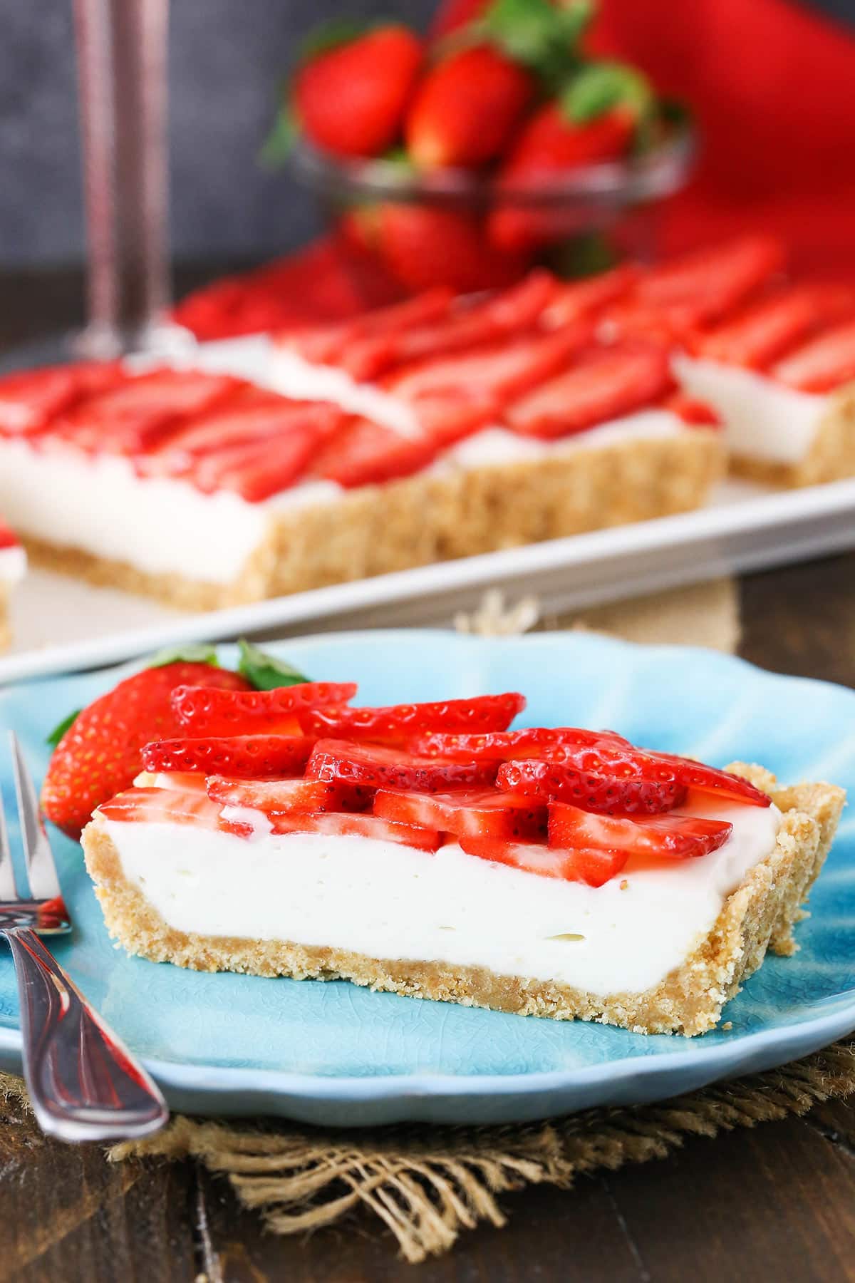 A slice of tart on a plate with the remaining slices on a platter behind it.