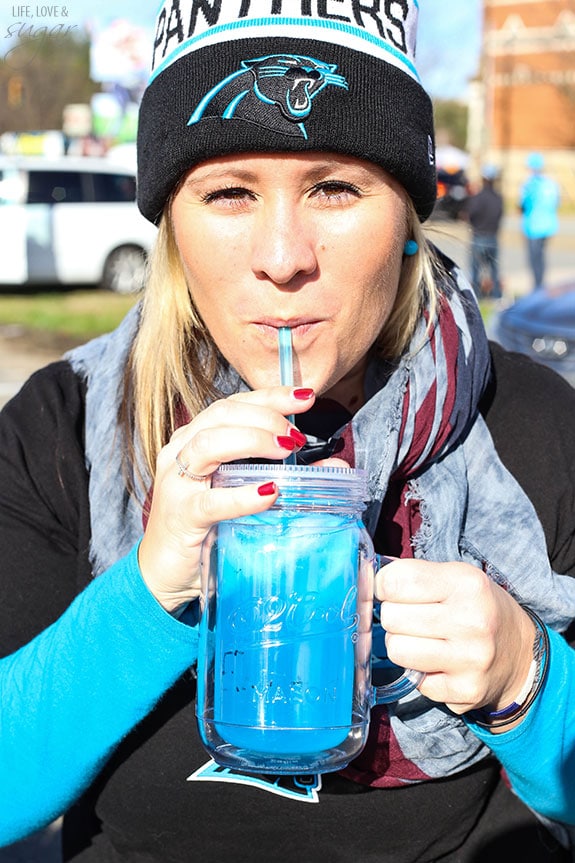 A female Panthers fan sipping a glass of Carolina Panther Punch 