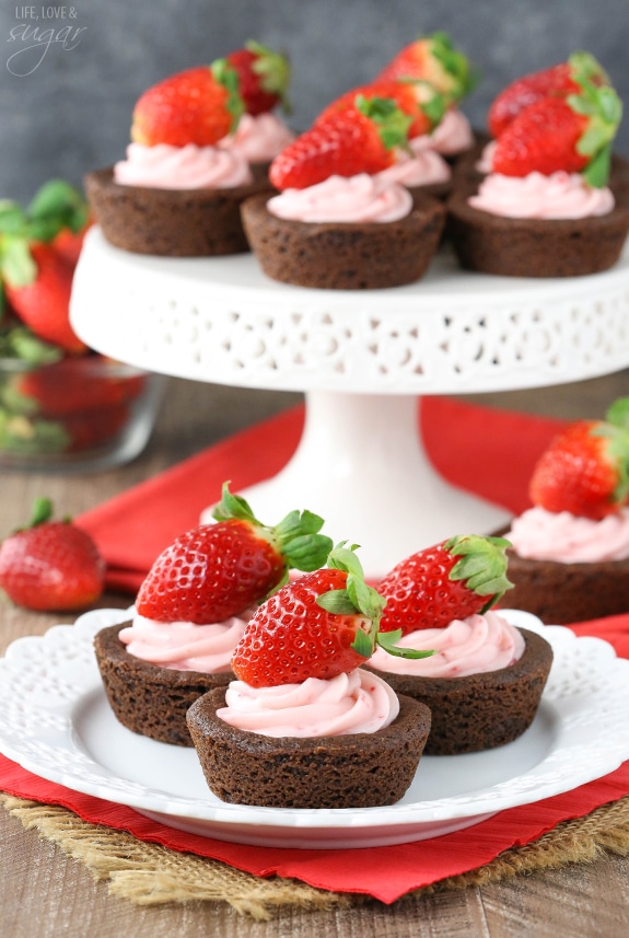 Strawberry Cheesecake Chocolate Cookie Cups on a plate and a cake stand