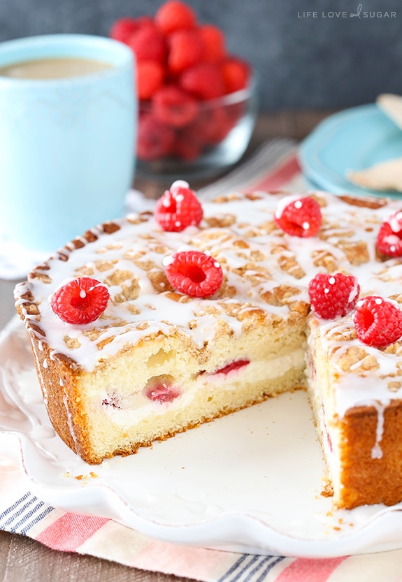 Raspberry Cream Cheese Coffee Cake on white platter with slice cut out