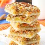 Carrot Cake Shortbread Bars stacked on a napkin with a bite taken out of the top one