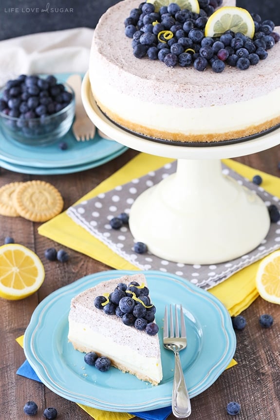Lemon Blueberry Mousse Cake on a cake stand with a slice on a plate in front