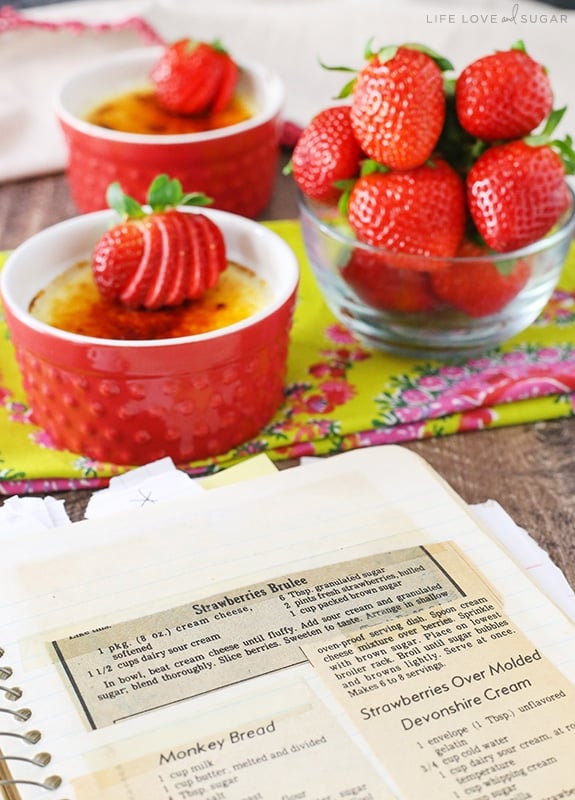 Strawberries Brûlée recipe in a notebook with ramkeins of strawberries brulee behind