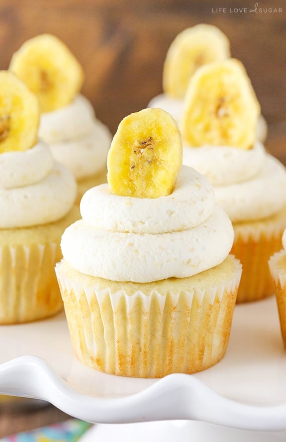 Close up of a Banana Cream Pie Cupcake on a white cake stand