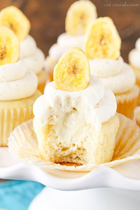 Banana Cream Pie cupcake with white frosting and a banana chip on top has a bite missing 
