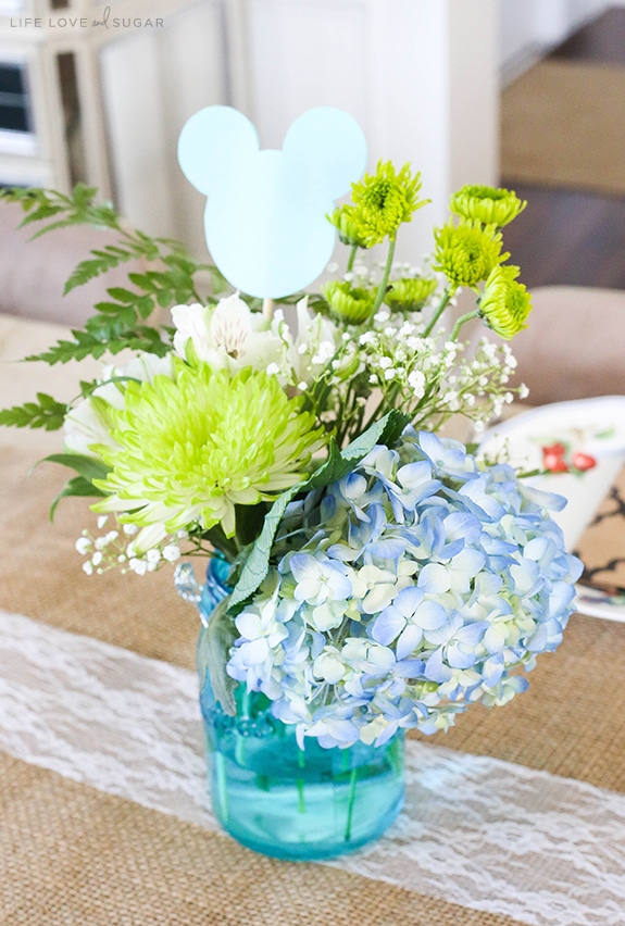 A Bouquet of Blue, Green and White Flowers and a Mickey Decoration in a Blue Jar