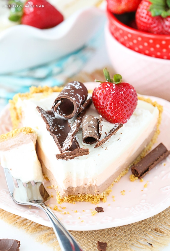 A slice of No Bake Neapolitan Cheesecake Pie on a plate with a bite on a fork
