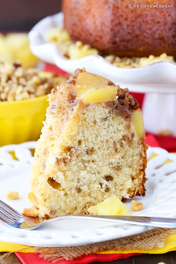 Close up side view of a slice of Pineapple Walnut Upside Down Cake on a plate with a fork