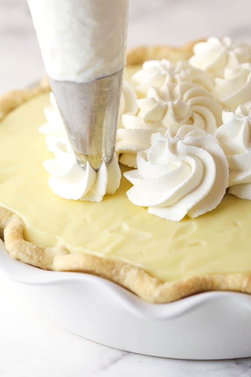 Piping whipped cream on banana cream pie