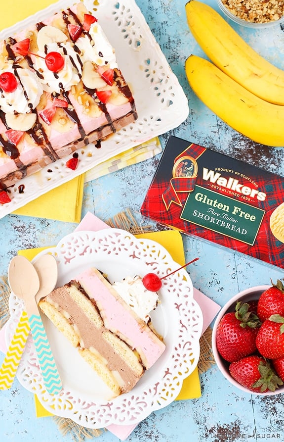 Overhead view of Banana Split Ice Cream Cake Loaf with a slice on a plate and ingredients nearby