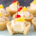 Pina Colada Cookie Cups on a cake stand with bite taken out of one