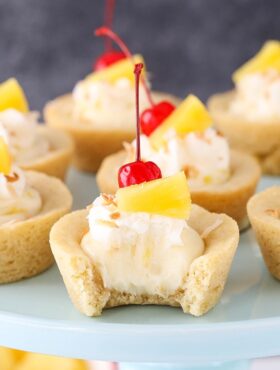 Pina Colada Cookie Cups on a cake stand with bite taken out of one