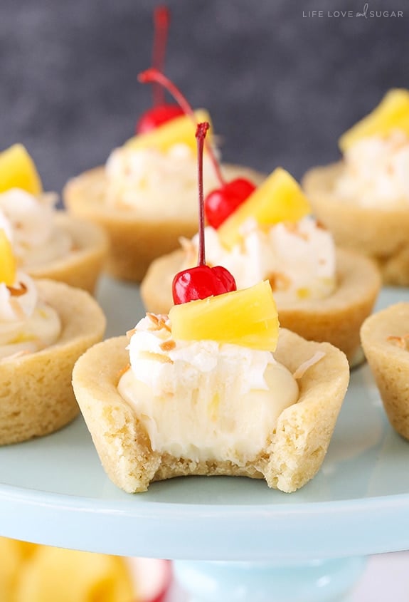 Pina Colada Cookie Cups on a cake stand with a bite out of one