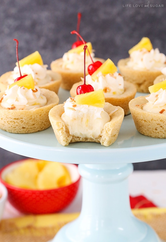 Pina Colada Cookie Cups on a cake stand with a bite out of one