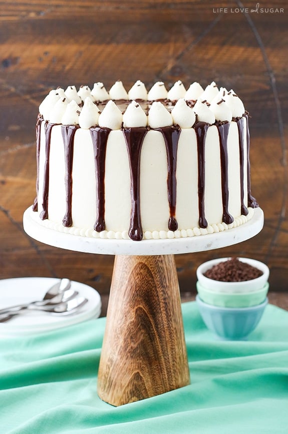 Baileys cake on a cake stand with white frosting and chocolate ganache