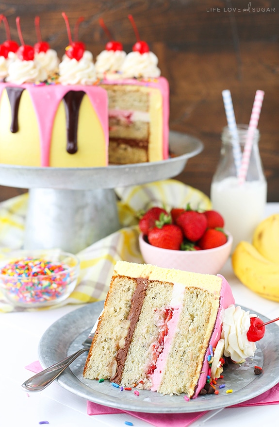 Banana Split Layer Cake - layers of moist banana cake with chocolate and strawberry buttercream filling, sliced bananas and strawberries, nuts, sprinkles and chocolate ganache! Banana split cake heaven!