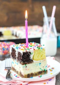 slice of ultimate birthday cake on white plate with pink candle on top